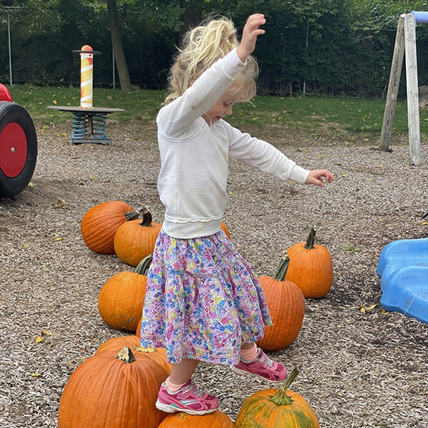 girl balancing on pumpkin